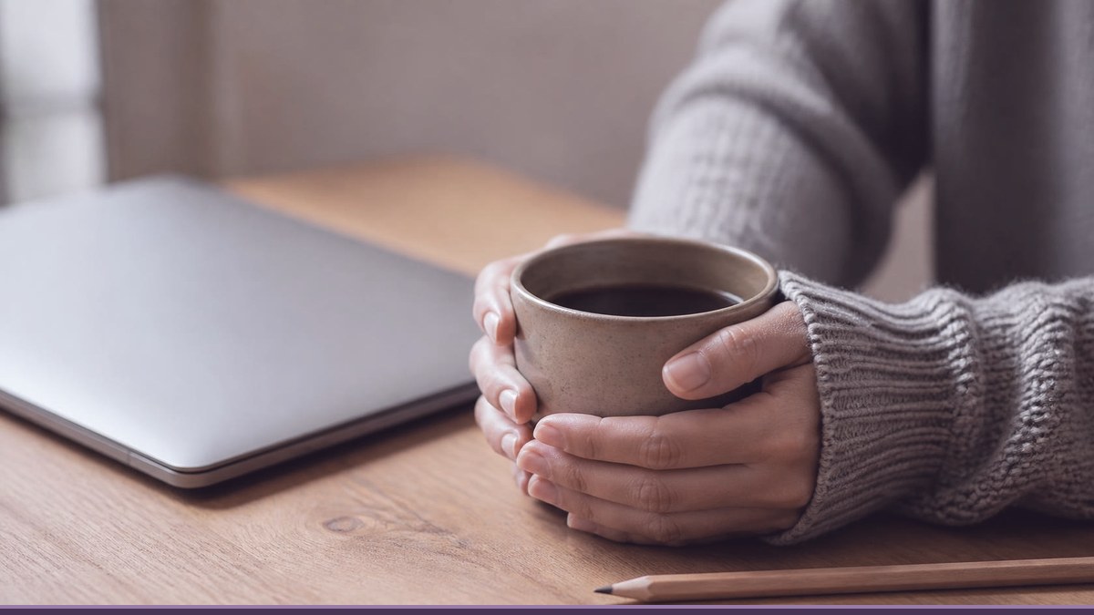 Hands holding a cup of coffee beside a closed laptop, taking a calm moment before fixing a WordPress site broken by an update