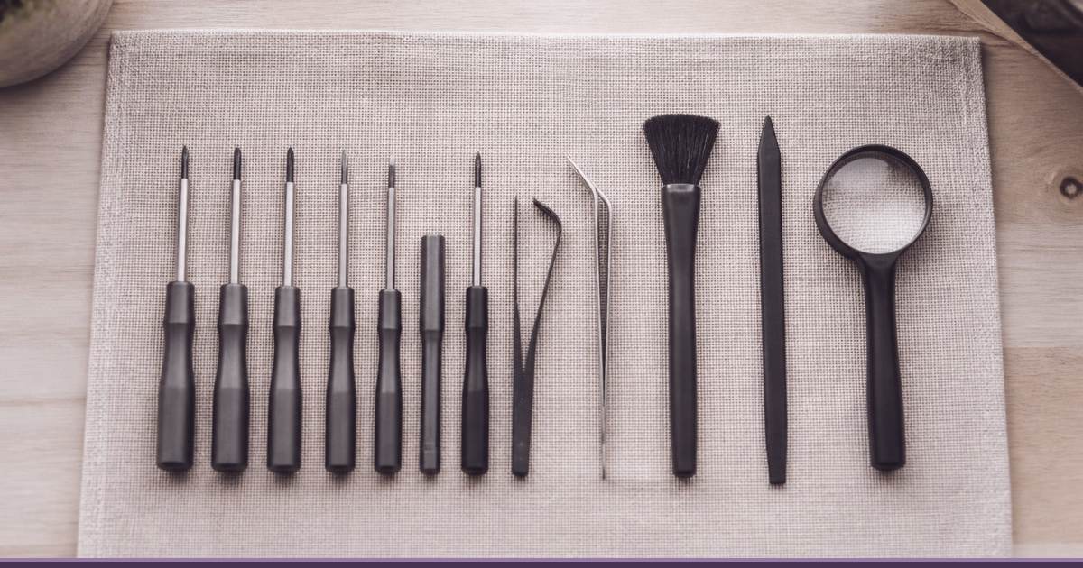 Precision screwdrivers, tweezers, a brush and a magnifier laid out neatly on a linen cloth, representing careful WordPress care plan work